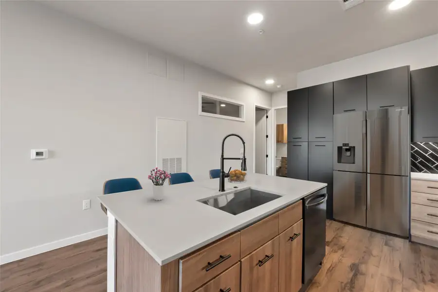 Kitchen with appliances with stainless steel finishes, a sink, wood finished floors, light countertops, and recessed lighting