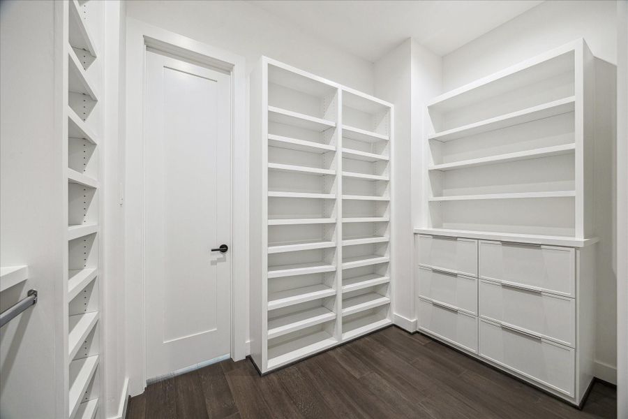 Generously sized dressing area featuring floor-to-ceiling shelving and dedicated storage zones. The streamlined built-ins provide both functionality and visual appeal, offering ample room for wardrobe organization while maintaining the home’s contemporary, minimalist design style.
