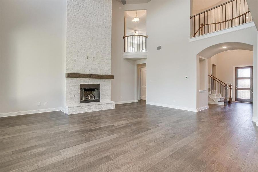 Unfurnished living room with a high ceiling, hardwood / wood-style flooring, and a fireplace