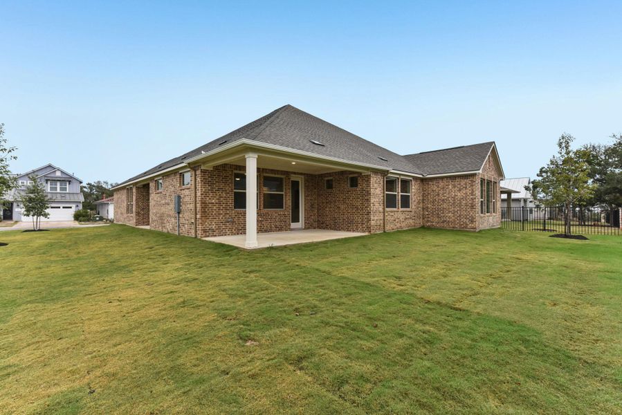Back of property featuring brick siding, a patio area, and roof with shingles
