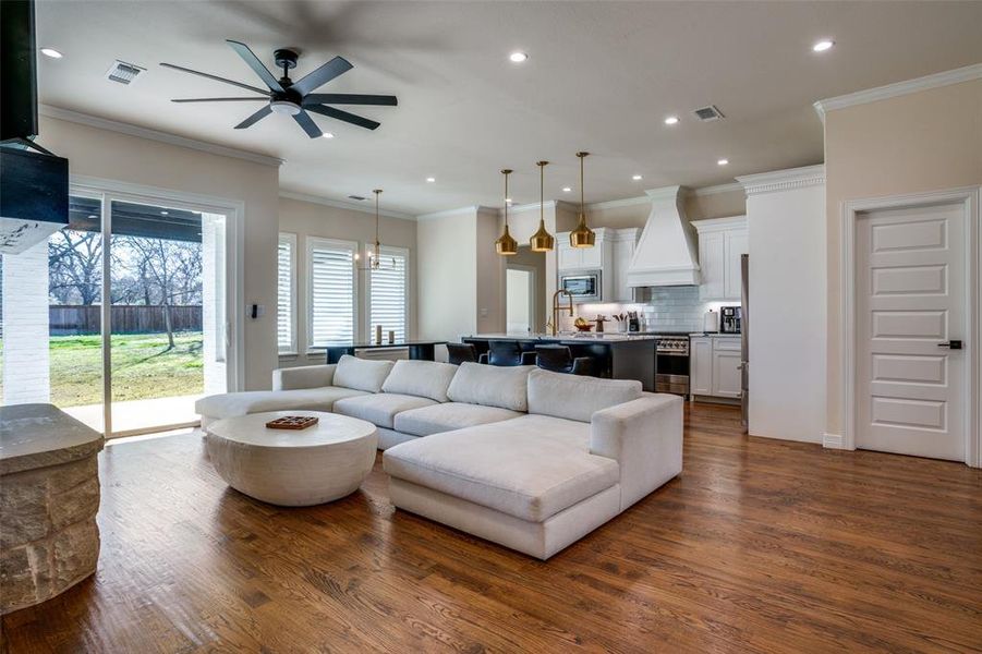 Living room featuring ceiling fan, dark wood-type flooring, and ornamental molding