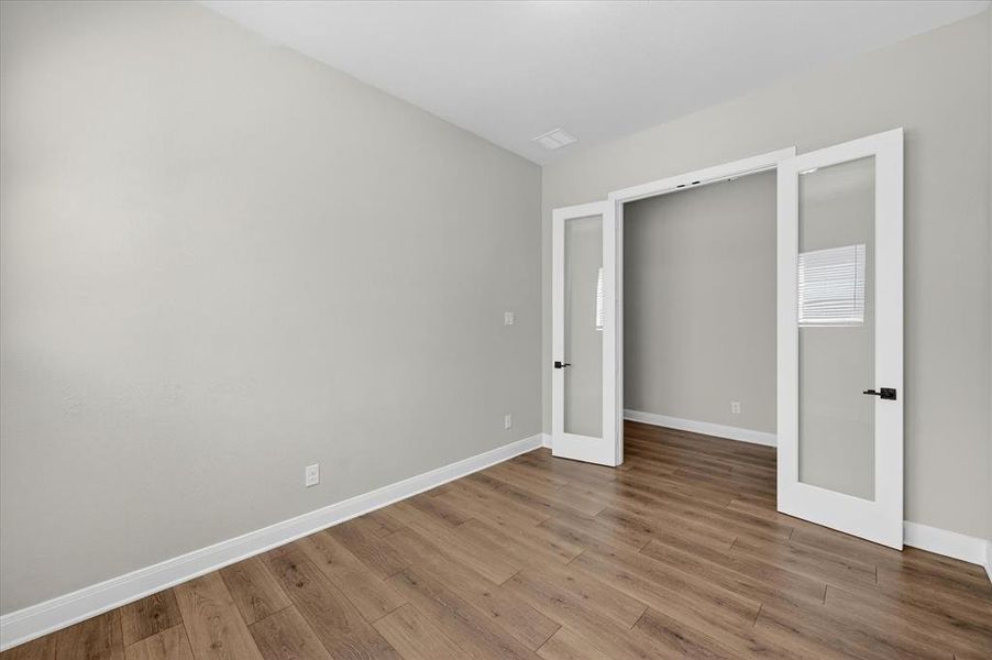 Office featuring wood-finish flooring, light gray walls, and white baseboards Office featuring wood-finish flooring, light gray walls, and white baseboards