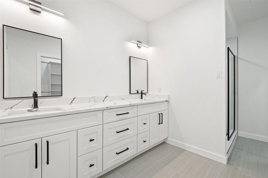 Bathroom featuring double vanity, a stall shower, and light tile patterned floors Bathroom featuring double vanity, a stall shower, and light tile patterned floors