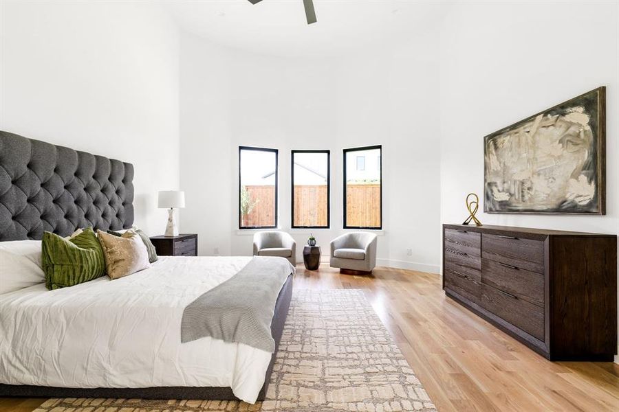 Bedroom with light wood-style floors, a towering ceiling, and ceiling fan Bedroom with light wood-style floors, a towering ceiling, and ceiling fan