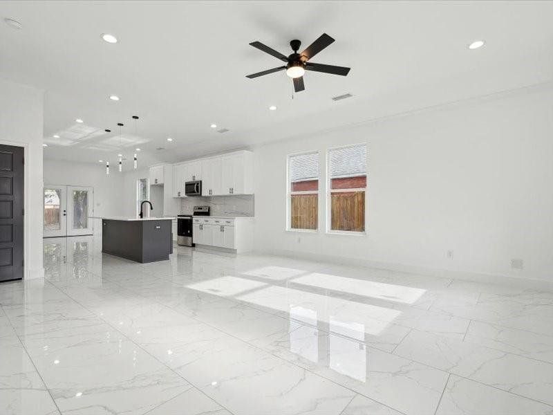 Unfurnished living room with ceiling fan and light tile patterned floors