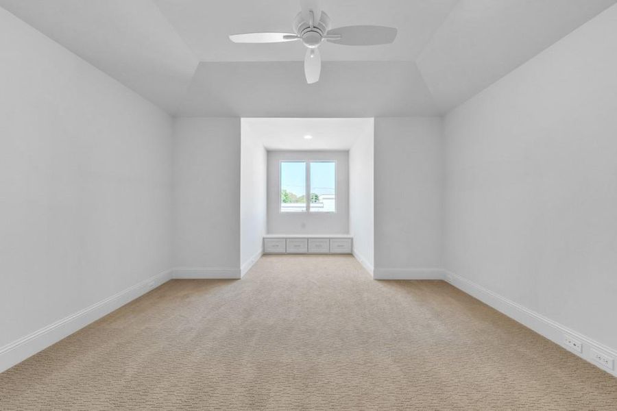Unfurnished room featuring light colored carpet, ceiling fan, baseboards, and lofted ceiling