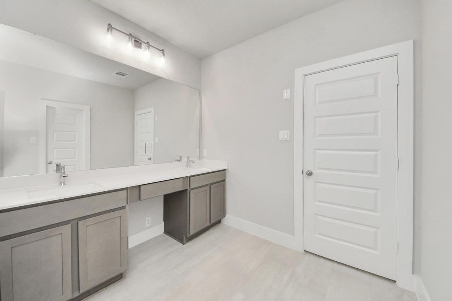 Elevate your daily routine at the elegant vanity, now equipped with double sinks, light countertops, modern hardware, and beautiful vanity lights.