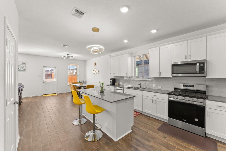 Kitchen with a center island, a breakfast bar, stainless steel appliances, dark countertops, and white cabinets