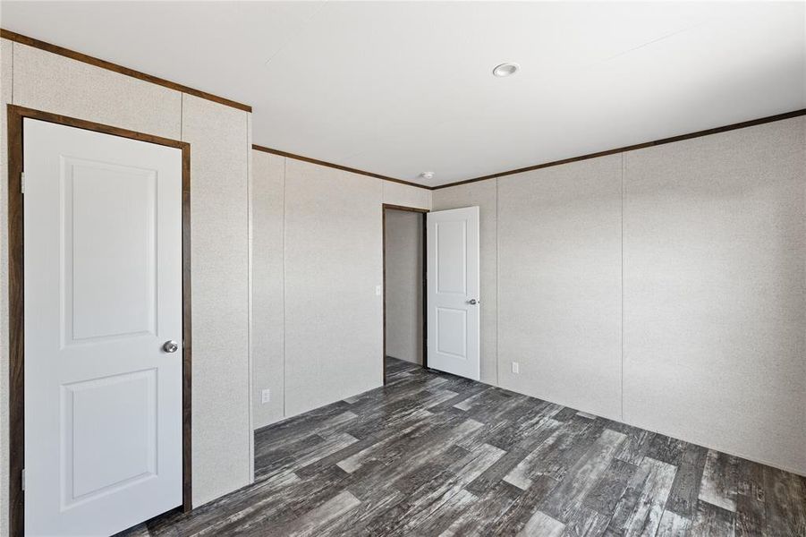 Spare room featuring crown molding and dark wood-type flooring