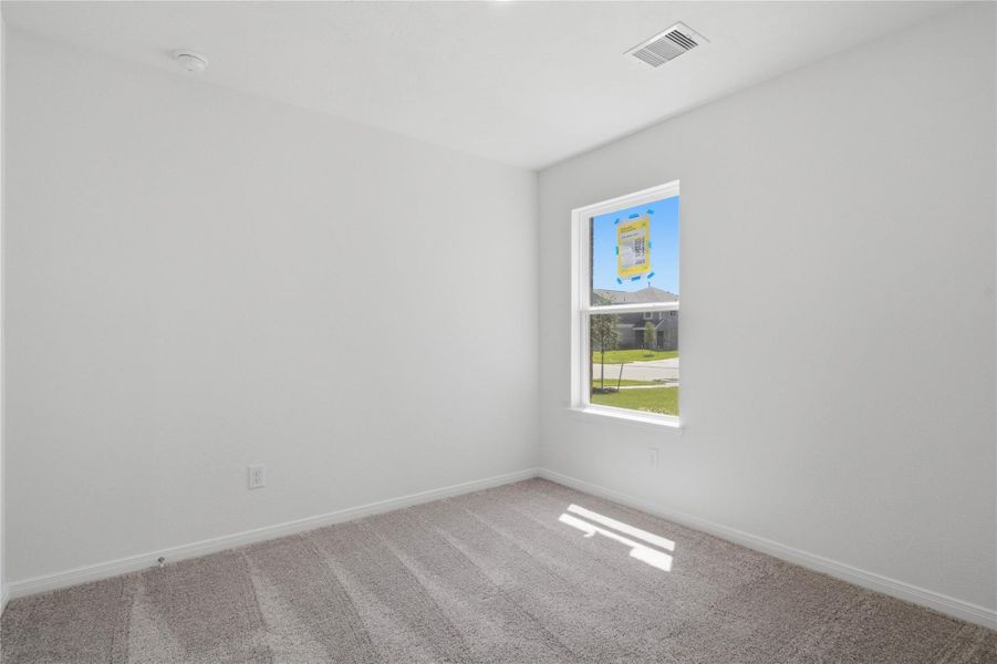 This secondary bedroom offers comfort and style with plush carpet flooring, neutral paint tones, a large window, and ample sized closet space.