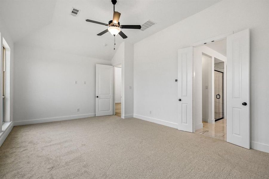 Unfurnished bedroom with light colored carpet, lofted ceiling, and ceiling fan