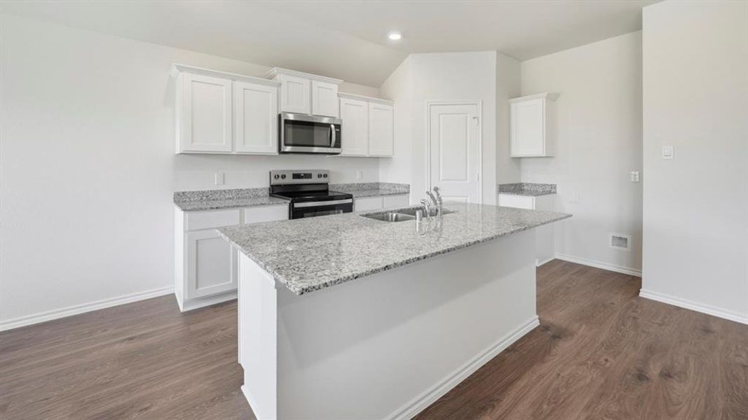 Kitchen featuring white cabinets, stainless steel appliances, a kitchen island with sink, light stone countertops, and dark wood-style flooring