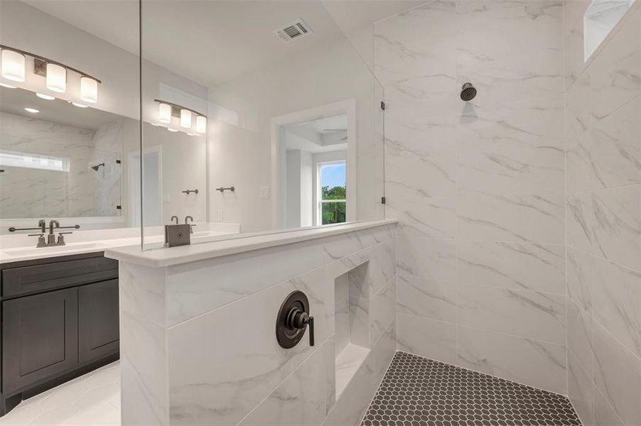Walk-in shower featuring gray penny tile flooring, marble-look wall tiling, and matte black fixtures Walk-in shower featuring gray penny tile flooring, marble-look wall tiling, and matte black fixtures