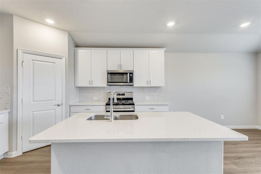 Kitchen with white cabinets, light stone counters, stainless steel appliances, light wood-style flooring, and recessed lighting