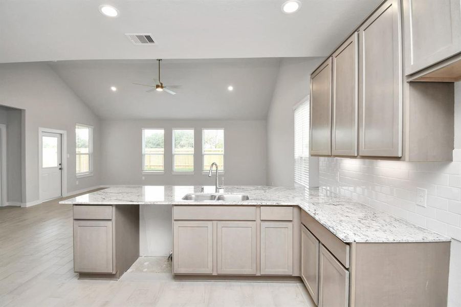 The kitchen is a culinary haven, featuring granite countertops, a tile backsplash, stainless steel appliances, 42” upper cabinets, and undercabinet lighting. Example photo of completed home with similar plan. Actual may vary.