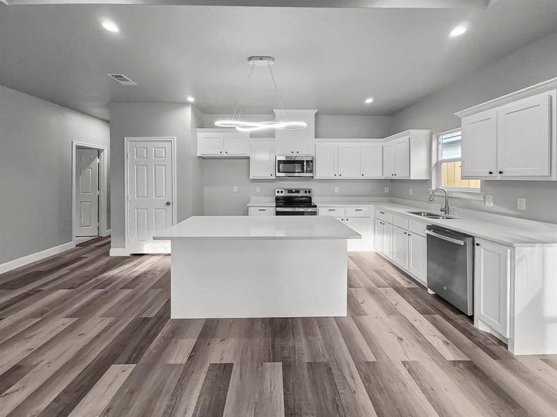 Kitchen with appliances with stainless steel finishes, a sink, a kitchen island, white cabinetry, and recessed lighting Kitchen with appliances with stainless steel finishes, a sink, a kitchen island, white cabinetry, and recessed lighting