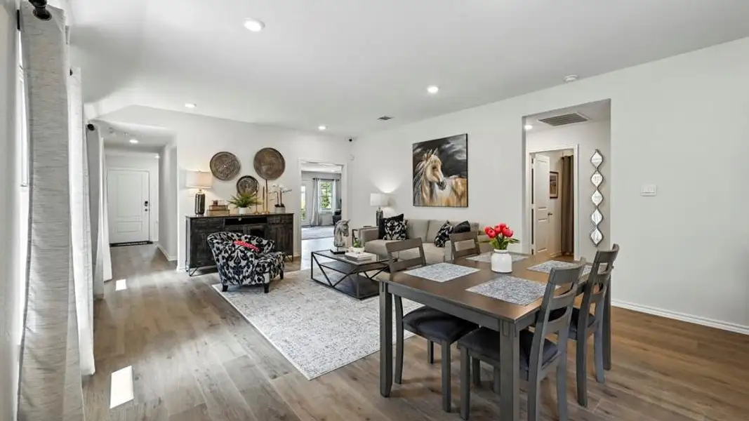 Open-concept living and dining area featuring wood-finish flooring, recessed lighting, and white wall finishes