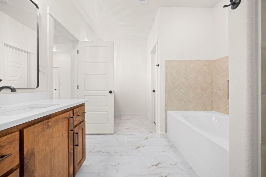 A well-appointed bath features a deep tub and a spacious vanity with clean lines.