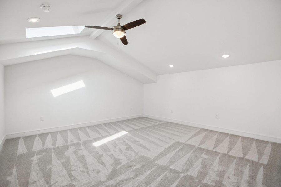 Bonus room with a skylight, light carpet, a ceiling fan, and beam ceiling