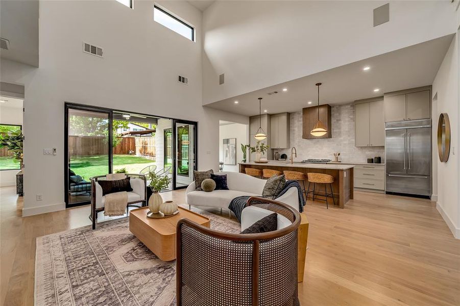 Living area with light wood-style flooring, a towering ceiling, and recessed lighting Living area with light wood-style flooring, a towering ceiling, and recessed lighting