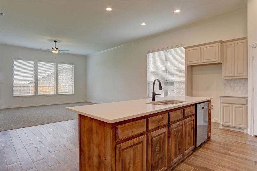 Kitchen with light hardwood / wood-style flooring, dishwasher, ceiling fan, an island with sink, and sink