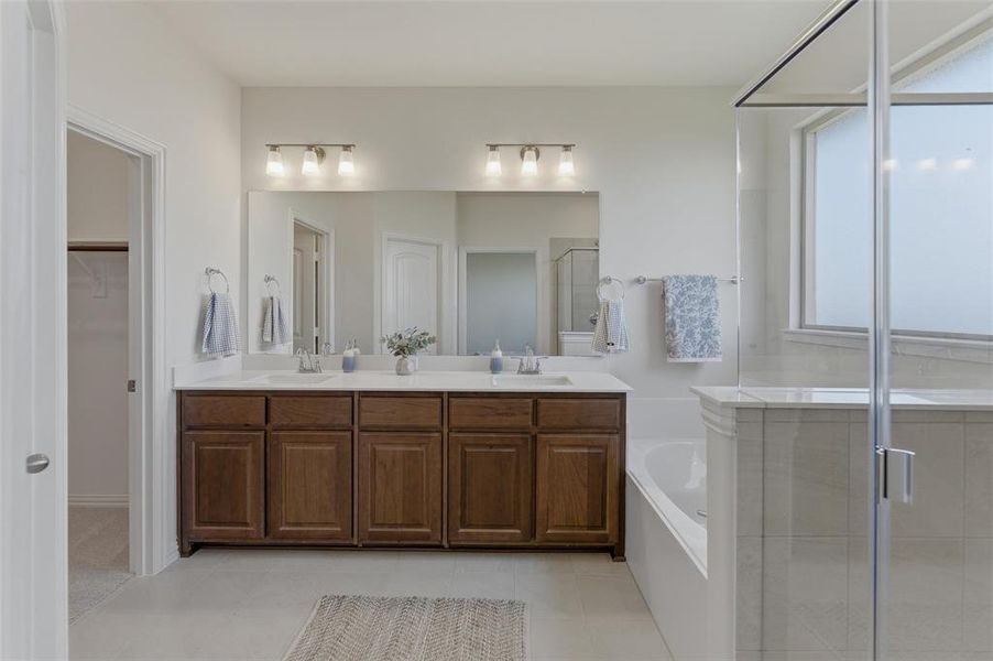 Dual vanity with wood-finish cabinetry, white countertops, and a full-width mirror
