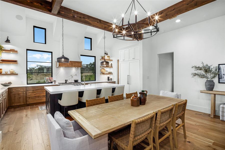 Dining room featuring a towering ceiling, light hardwood / wood-style flooring, and beamed ceiling