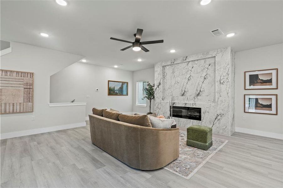 Living room featuring a ceiling fan, a high end fireplace, light wood-style flooring, and recessed lighting Living room featuring a ceiling fan, a high end fireplace, light wood-style flooring, and recessed lighting