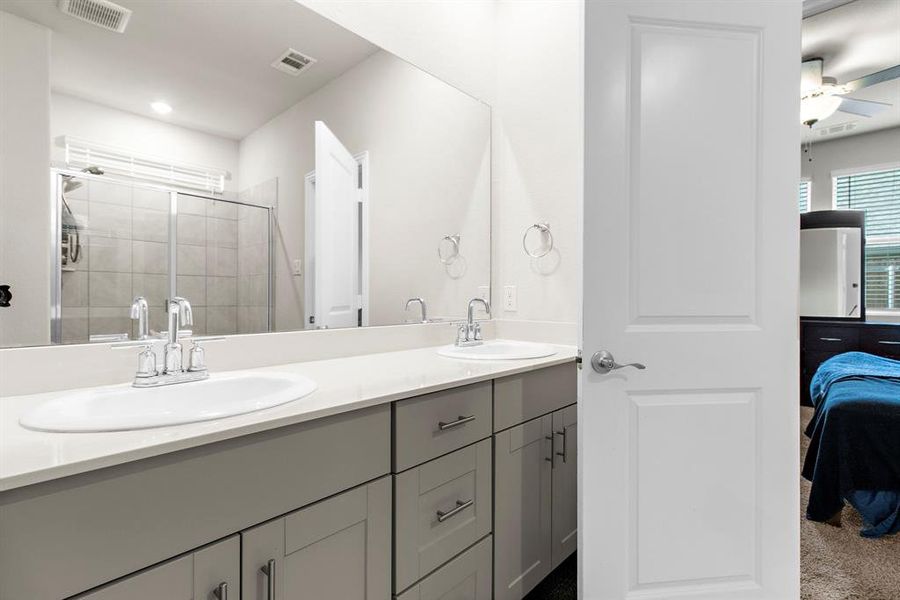Ensuite bathroom with double vanity, a stall shower, and ceiling fan Ensuite bathroom with double vanity, a stall shower, and ceiling fan