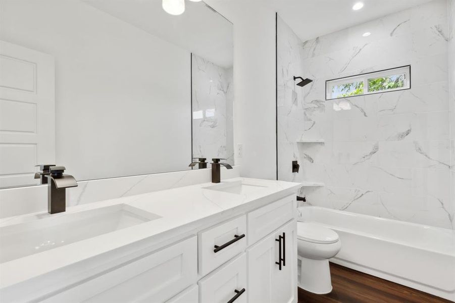 Full bathroom with vanity, toilet, wood-type flooring, and tiled shower / bath combo