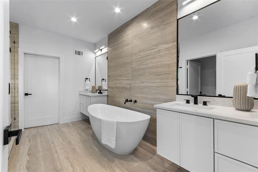 Freestanding soaking tub with a floor-mounted faucet, complemented by dual vanities with integrated sinks and matte black fixtures Freestanding soaking tub with a floor-mounted faucet, complemented by dual vanities with integrated sinks and matte black fixtures