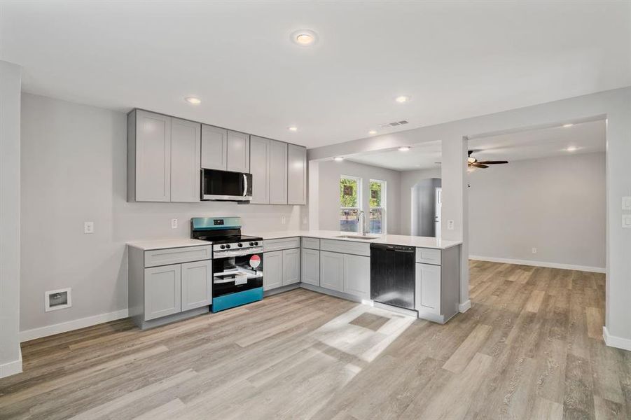 Kitchen with dishwasher, light hardwood / wood-style flooring, sink, range, and gray cabinets