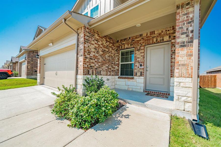 Entrance to property with board and batten siding, a porch, driveway, a garage, and brick siding Entrance to property with board and batten siding, a porch, driveway, a garage, and brick siding