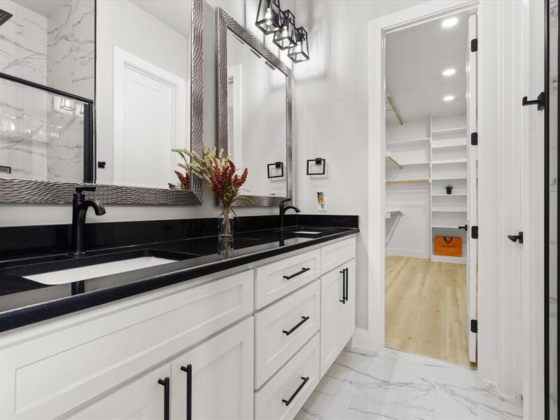Dual vanity with black countertops and undermount sinks, white cabinetry, and matte black hardware Dual vanity with black countertops and undermount sinks, white cabinetry, and matte black hardware