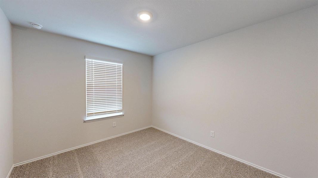 Empty room with light carpet and a smoke detector