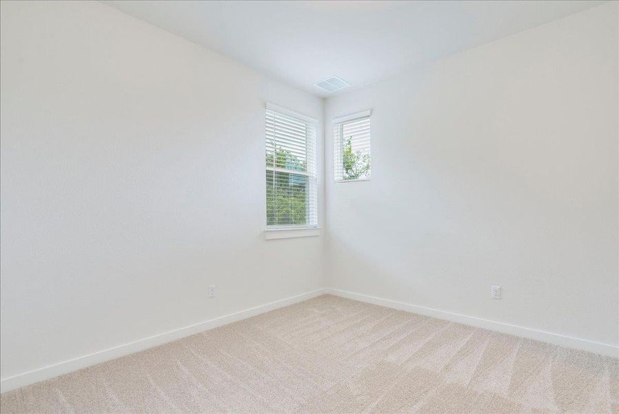 An airy bedroom with dual windows offers a tranquil, sun-filled retreat.