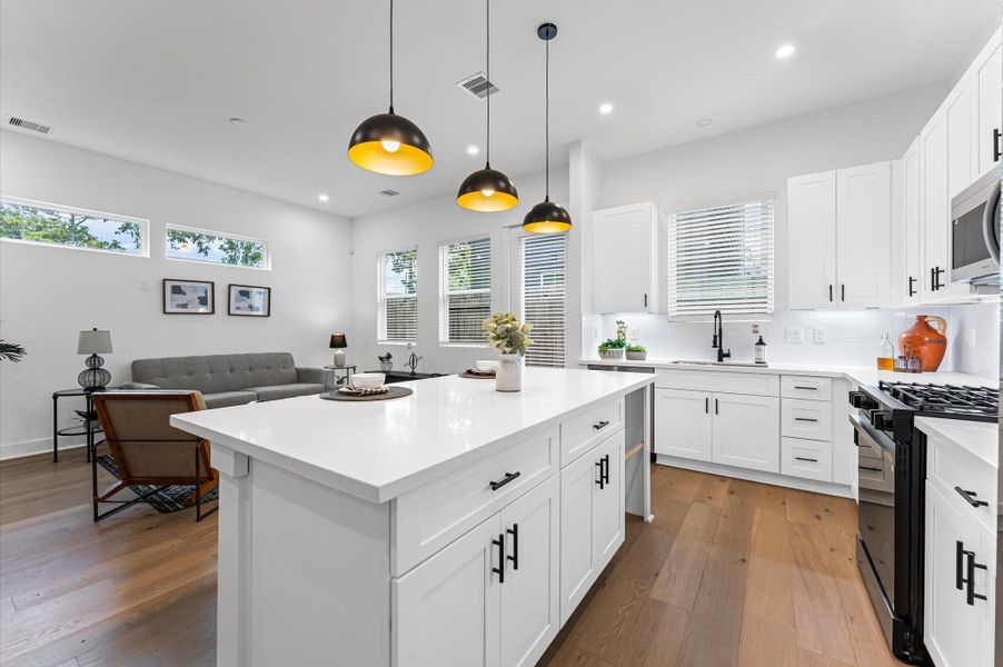 This centrally positioned kitchen island serves as a stylish anchor within the open-concept layout, offering clear sightlines to the dining area, living space, and the backyard beyond. Its placement encourages seamless interaction, whether prepping meals or entertaining guests, while natural light pours in through the nearby windows. The island’s sleek design and functional surface make it a hub of activity, framed by elegant finishes tying together comfort and sophistication.