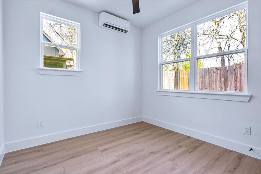 Unfurnished room featuring light wood-style floors, baseboards, a ceiling fan, and a wall mounted AC