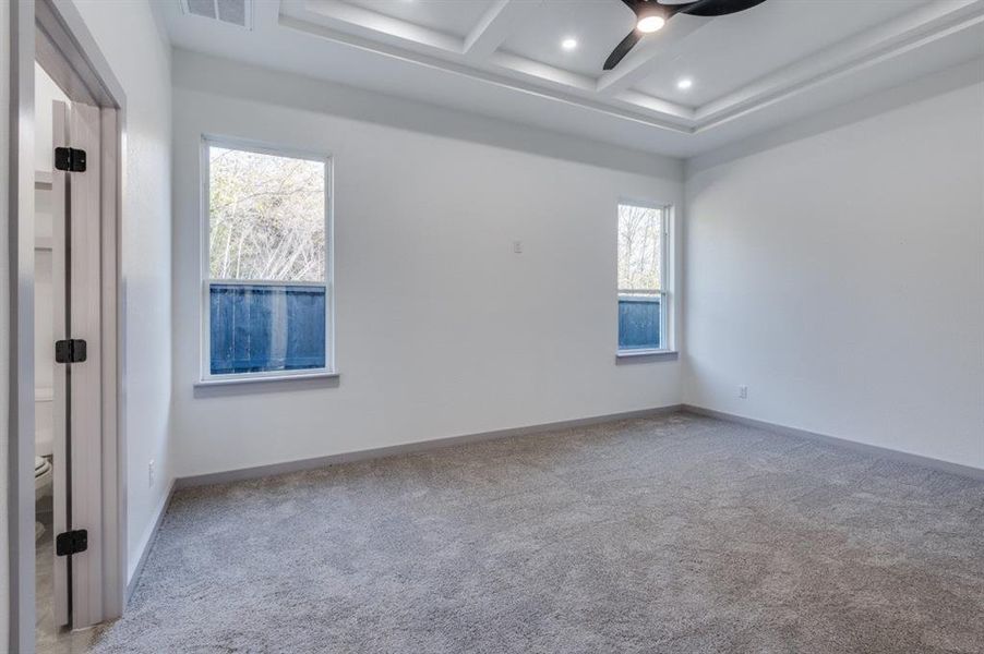 Carpeted spare room with beamed ceiling, ceiling fan, a wealth of natural light, and coffered ceiling