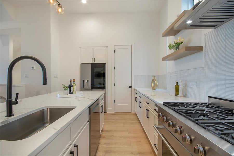 Kitchen with open shelves, light stone countertops, appliances with stainless steel finishes, and white cabinetry Kitchen with open shelves, light stone countertops, appliances with stainless steel finishes, and white cabinetry