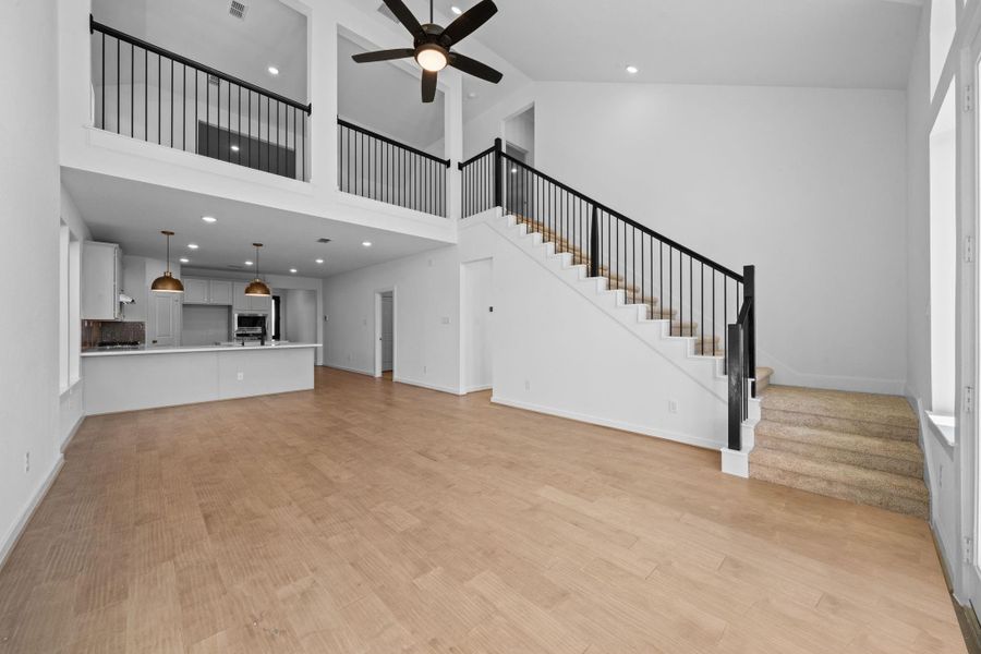 A long, grand staircase sweeps upward with graceful lines, featuring elegant railings and soft lighting that highlight its architectural beauty. At the top, the stairs open into a spacious gameroom, setting a dramatic and inviting transition from the main level to the home’s entertainment hub.