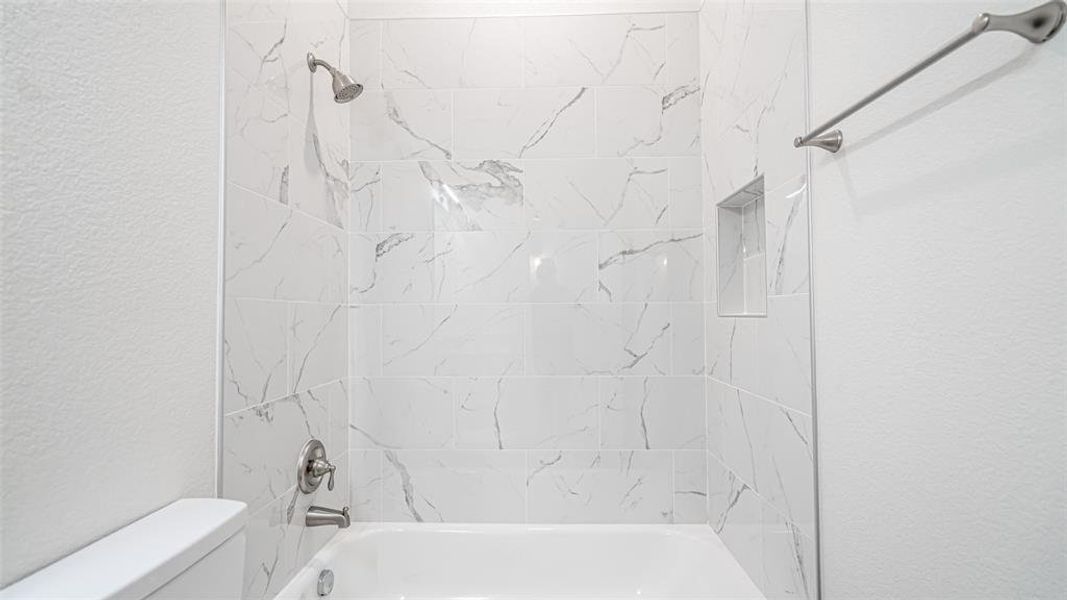 Bathroom with tiled shower / bath combo and toilet