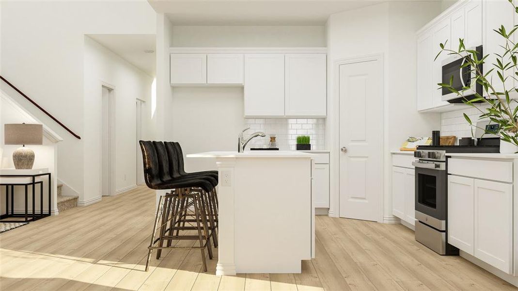 Kitchen with white cabinetry, appliances with stainless steel finishes, a center island with sink, and light wood-type flooring