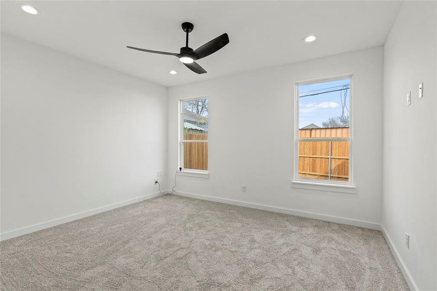 Spare room featuring a wealth of natural light, light colored carpet, and ceiling fan