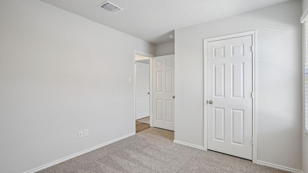 Unfurnished bedroom with light colored carpet and baseboards