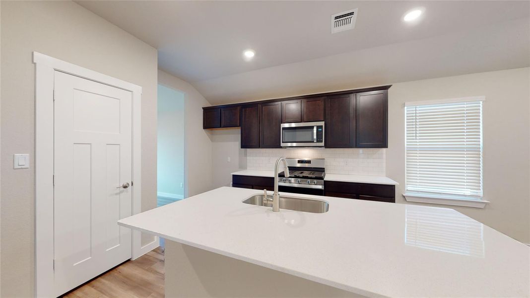 A well-appointed kitchen features a large island, contemporary dark cabinetry, and sleek stainless steel appliances. A well-appointed kitchen features a large island, contemporary dark cabinetry, and sleek stainless steel appliances.