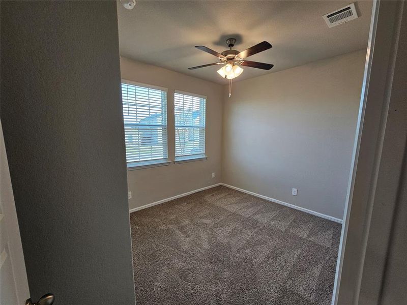 Front bedroom featuring ceiling fan, window coverings and a ceiling fan.