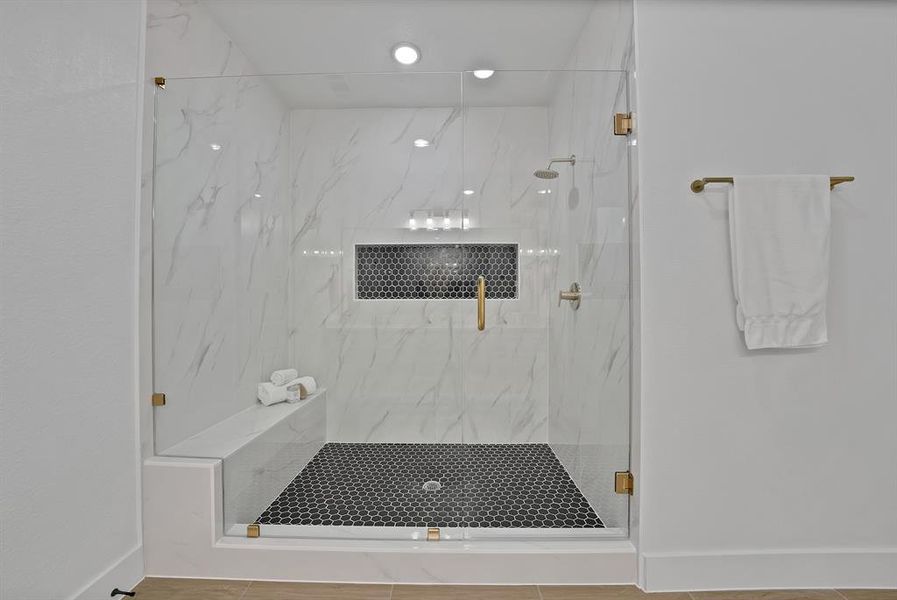 Bathroom with a marble finish shower and baseboards