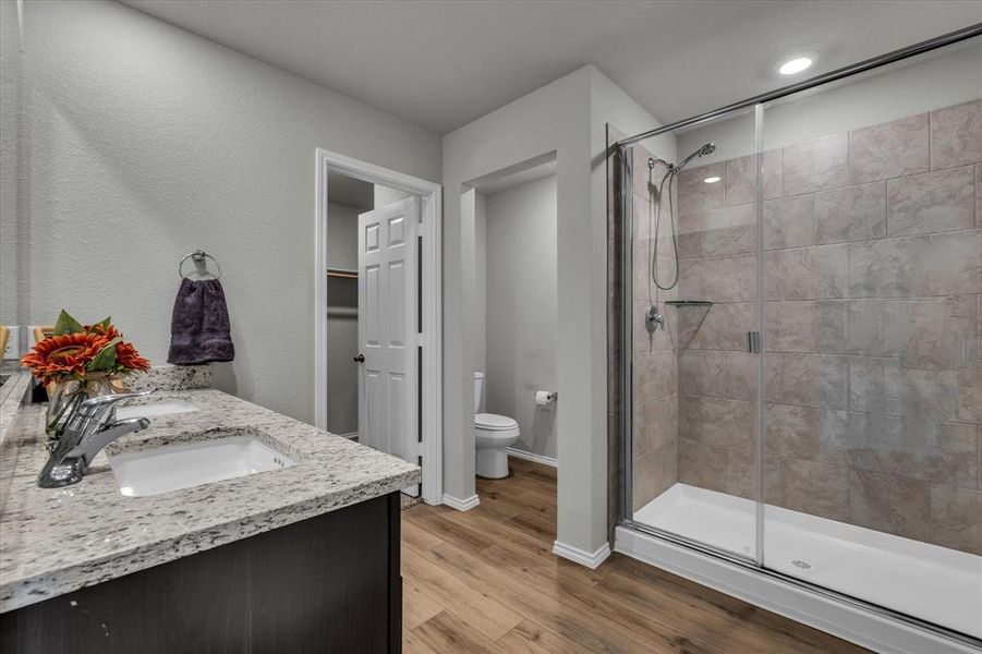 Primary bathroom features dual vanities, granite counters, a private toilet room, spacious shower, and access to the large walk-in closet.