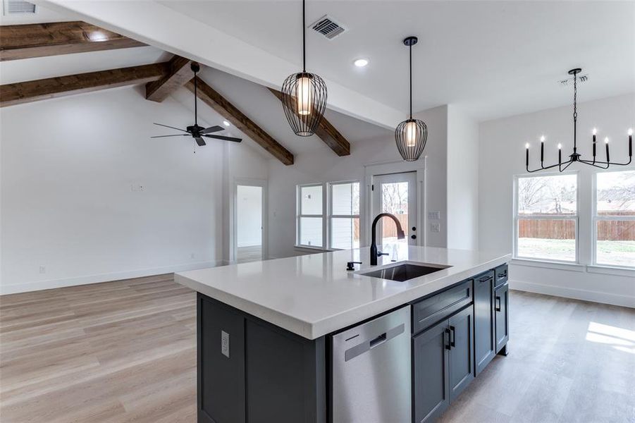 Kitchen with a sink, vaulted ceiling with beams, visible vents, and dishwasher